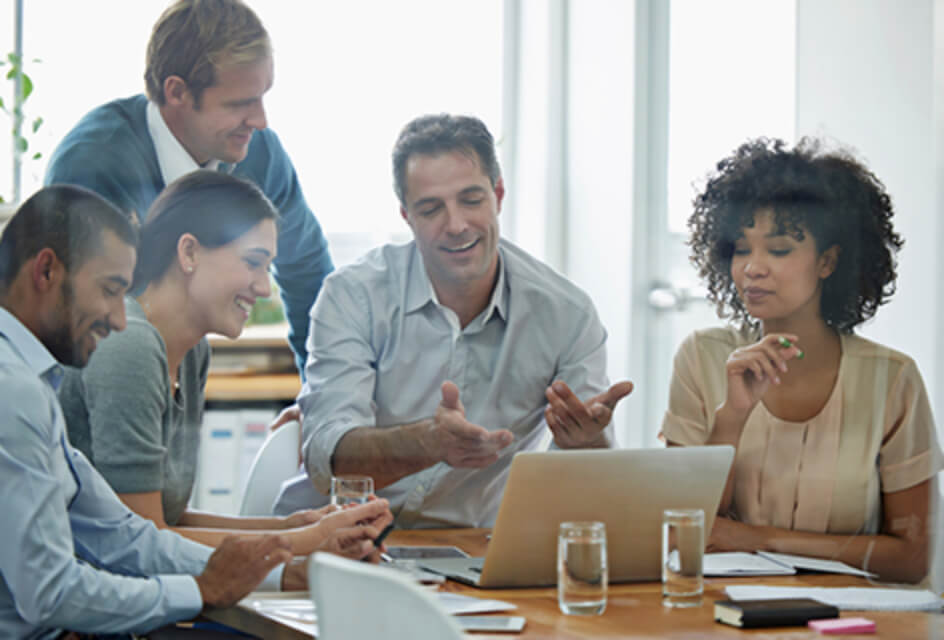 group of business people gathered around laptop